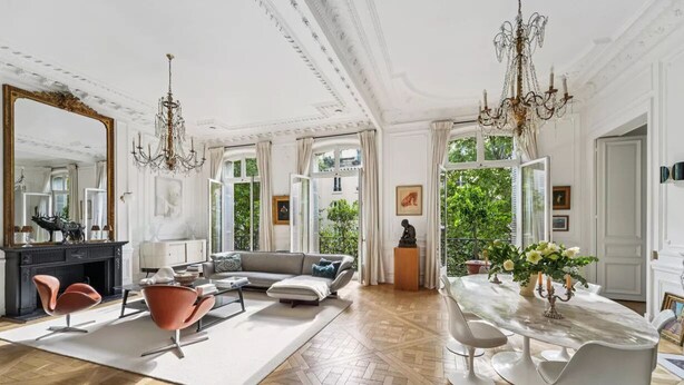 A spacious living room with a fireplace, a large mirror, a chandelier, and a dining area with a table and chairs. - A 300m² Estate of Art, Elegance & Architectural Majesty:Blvd.de la Tour-Maubourg (Paris)