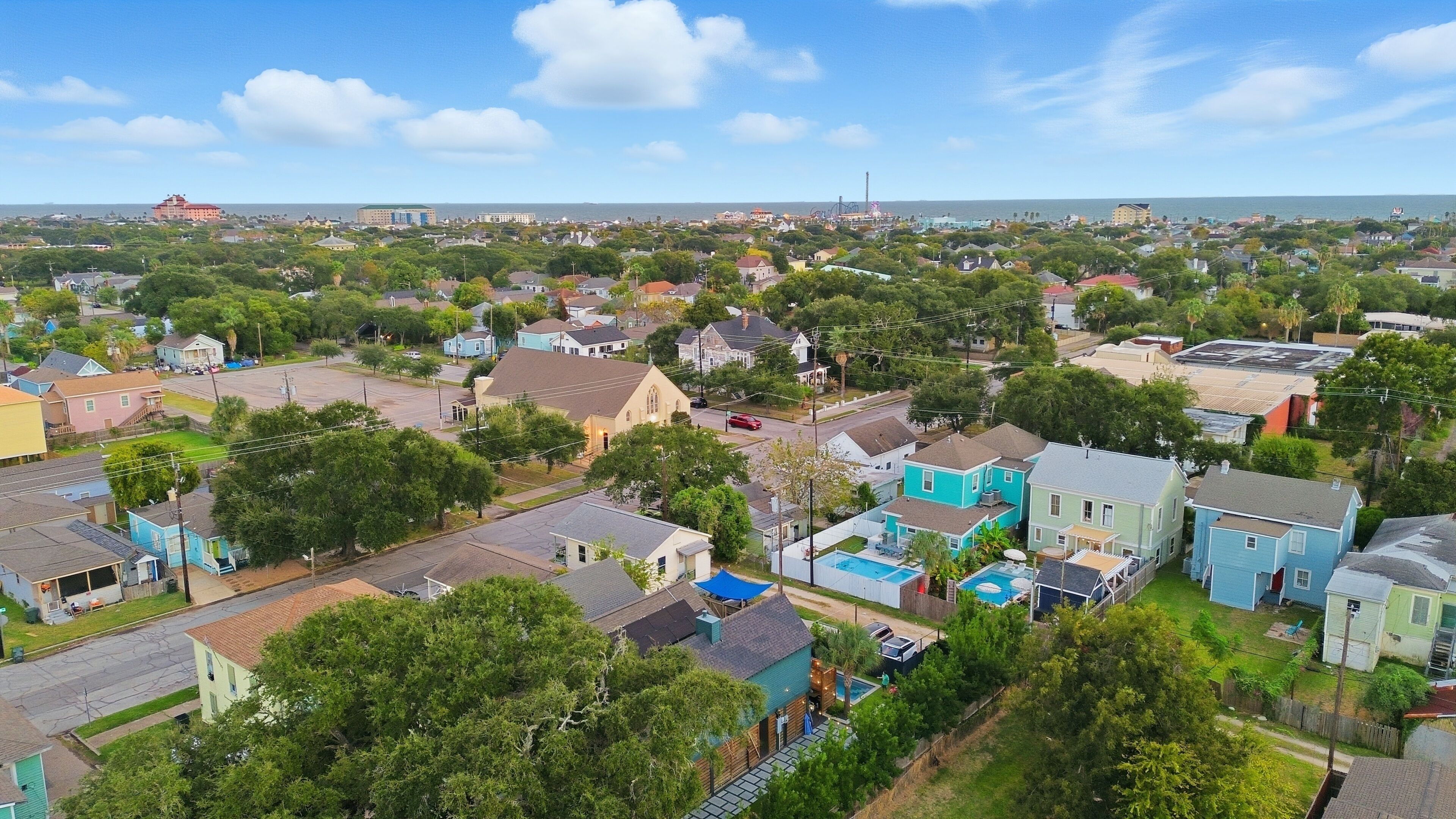 A residential area with houses, trees, and a distant view of the ocean.