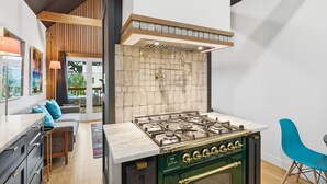 Een moderne keuken met een gasfornuis, houten balken in het plafond en een betegelde muur.