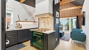 Een moderne keuken met een centraal eiland, een gaskookplaat, donkere kastjes en een houten plafond.