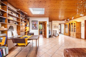 A spacious room with a wooden ceiling, a dining area with a table and chairs, a bookshelf, and a view through an open door. - Very comfortable house in the Hamburg area (Kisdorf)
