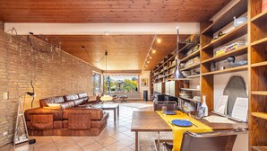 A modern living room with a leather sofa, wooden dining table, and a brick wall. - Very comfortable house in the Hamburg area (Kisdorf)