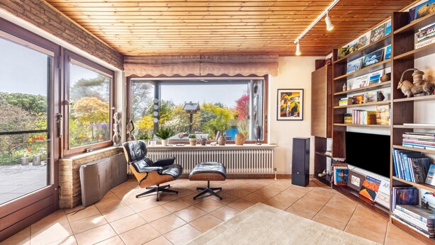 A room with a large window, a bookshelf, a radiator, a chair, and a rug. - Very comfortable house in the Hamburg area (Kisdorf)