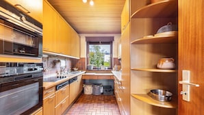 A modern kitchen with wooden cabinets, stainless steel appliances, and a herringbone floor pattern. - Very comfortable house in the Hamburg area (Kisdorf)