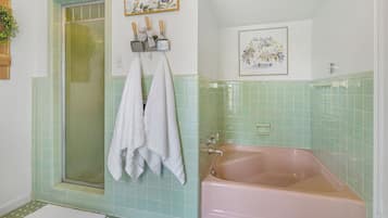 Un baño con ducha, bañera y dos toallas colgadas en la pared.
