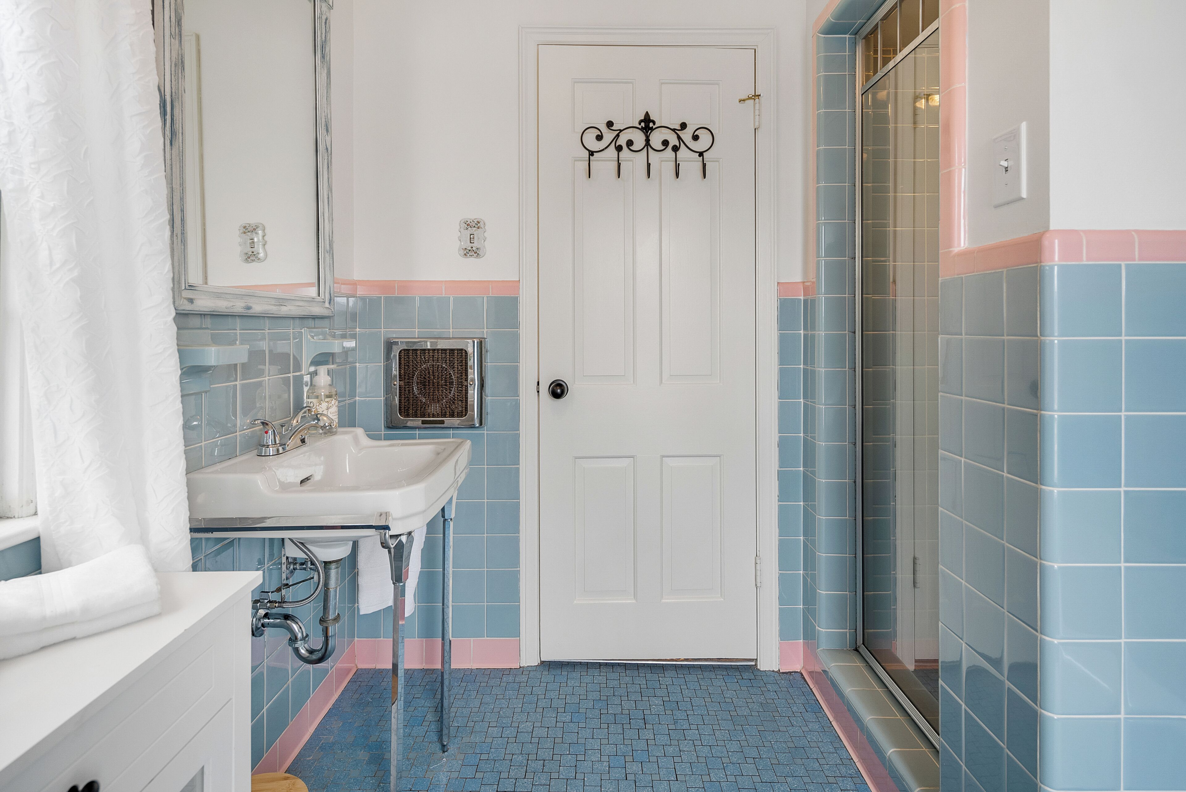 Un baño con un lavabo blanco, una puerta con pomo decorativo y paredes con azulejos azules.