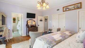 Un dormitorio con cama, escritorio, silla, cómoda, espejo y candelabro.