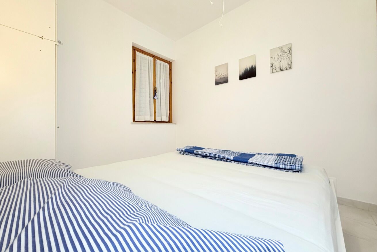 Ein Schlafzimmer mit einem Bett, einem Fenster und drei an der Wand befestigten Kunstwerken.