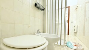 Et badeværelse med toilet, bidet og bruseområde.
