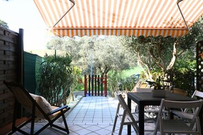 An outdoor patio area with a striped awning, a gate, and a table with chairs. - M450 - Marcelli, two-room apartment with patio (Marcelli)