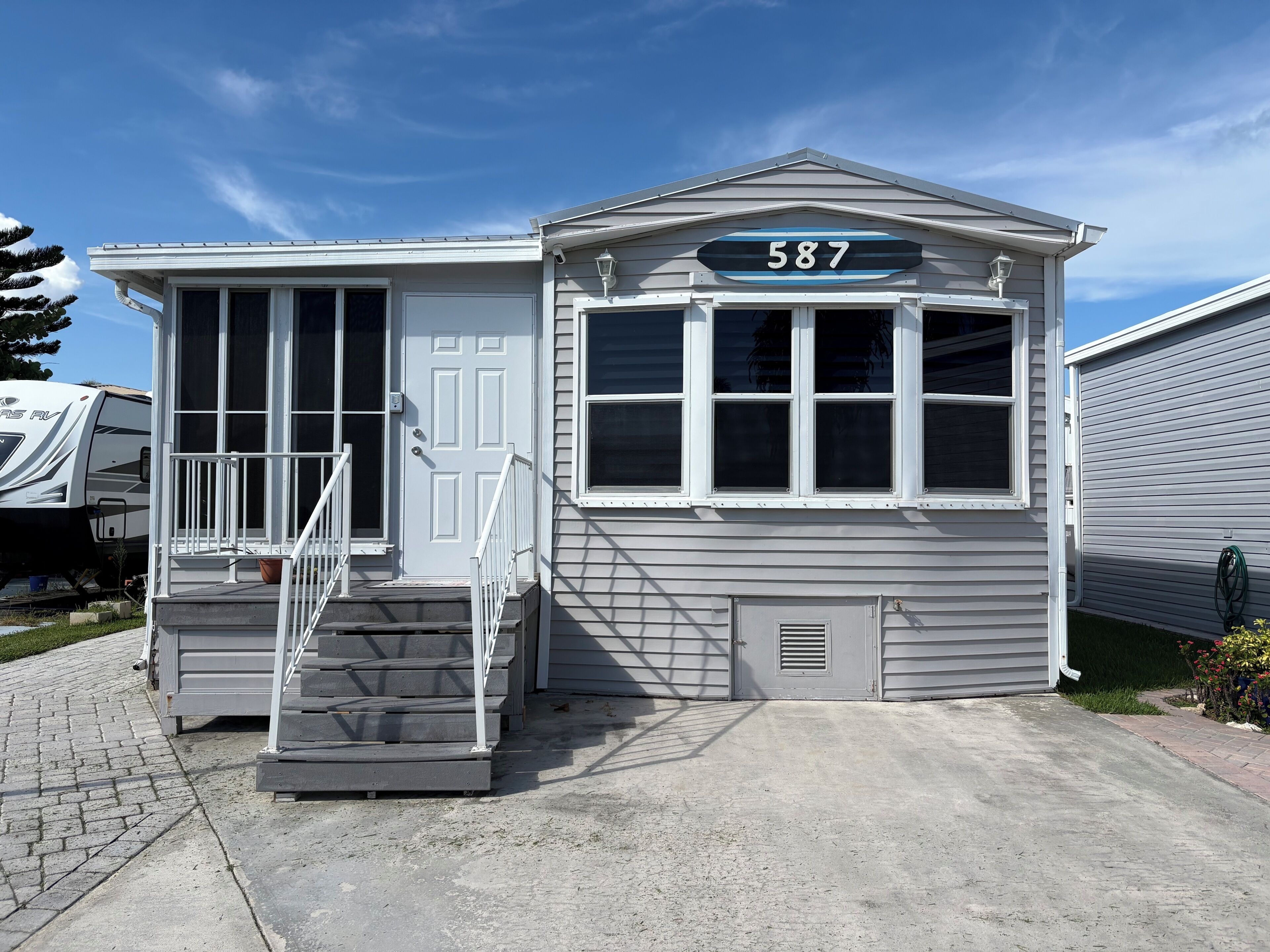 A small, single-story building with a front door, a set of stairs, and a mailbox.