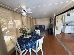 A dining area with a round table, white chairs, and a ceiling fan.