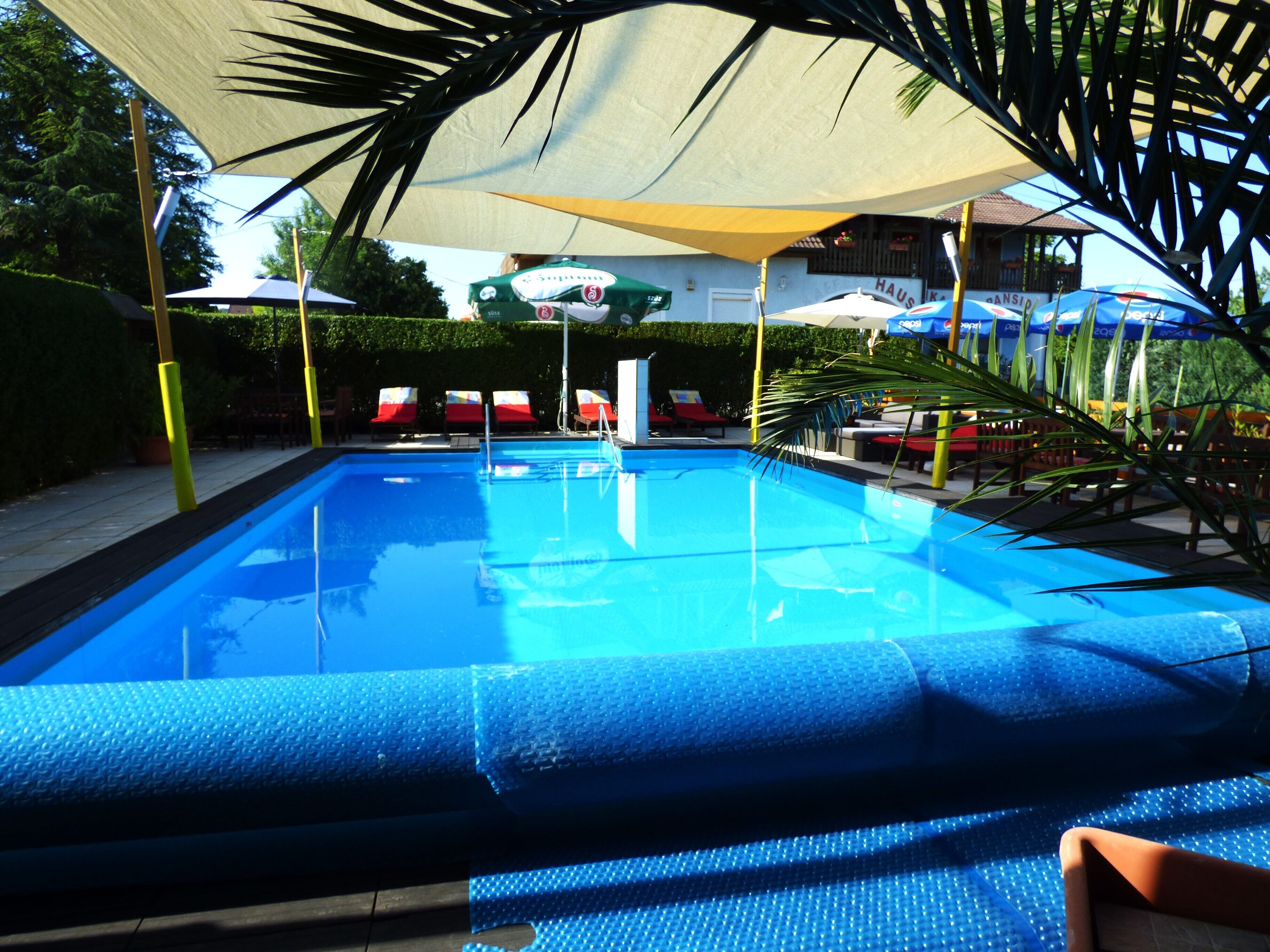A swimming pool with lounge chairs and umbrellas.