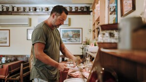 Una persona preparando comida en una cocina con muebles de madera y diversos utensilios de cocina.