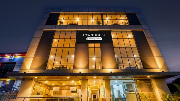 A modern building with a sign reading "TOWNHOUSE" and "Company Serviced". - Deluxeabirami Grand Inn (Kodaikanal)