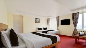 A hotel room with two beds, a television, and a window with curtains. - Deluxeabirami Grand Inn (Kodaikanal)