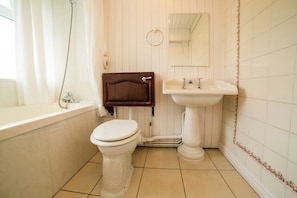 A bathroom with a white toilet, a wooden cabinet, a white sink, and a mirror above the sink. - Royal Hotel (Gateshead)