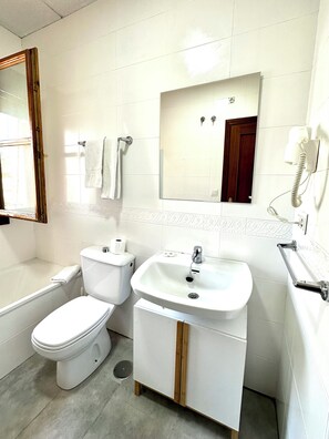 Een badkamer met toilet, wastafel en spiegel.