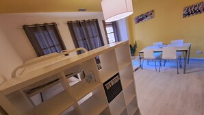 A room with a bunk bed, a dining area with a table and chairs, and a wall with a poster.