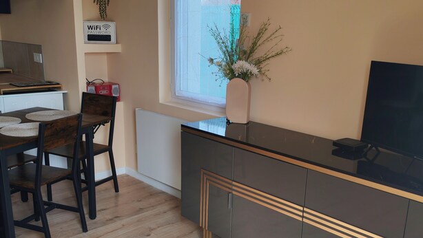A modern kitchen with a dining area, a window with a view, and a WiFi password sign. - 1-bedroom house 8 minutes from the 24H circuit (Allonnes)