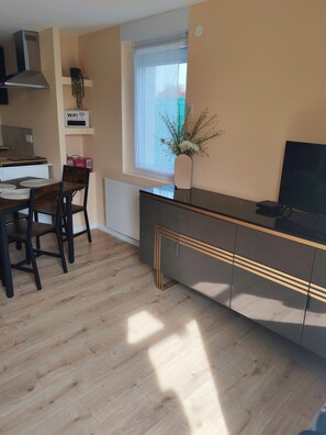 A modern kitchen with a dining area, a window with a view, and a WiFi password sign. - 1-bedroom house 8 minutes from the 24H circuit (Allonnes)