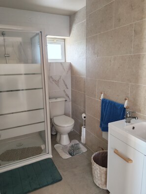 A bathroom with a shower, toilet, sink, and a window. - 1-bedroom house 8 minutes from the 24H circuit (Allonnes)