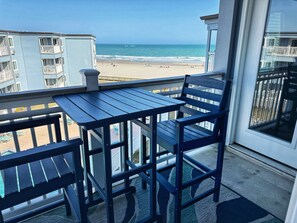 Un balcon avec une table et des chaises donnant sur une plage.
