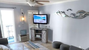 A living room with a sofa, coffee table, TV, and decorative wall art. - Oceanfront•Steps to beach•Pool view•Sleeps 6 (Myrtle beach)