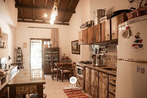 Cucina con mobili in legno, un frigorifero e una zona pranzo con sedie e tavolo.