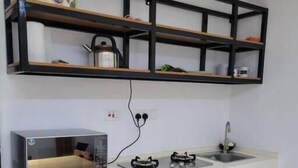 Een compacte keuken met een wasmachine, een magnetron, een spoelbak en een fornuis.