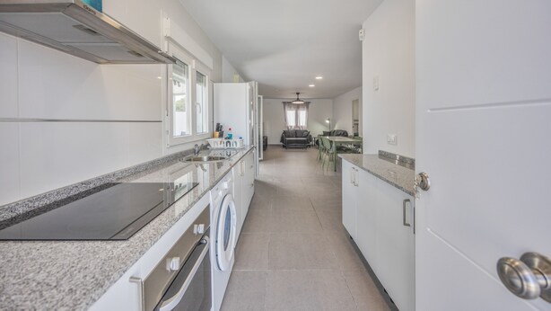 Een moderne keuken met een ingebouwde wasmachine, een magnetron en een kookplaat.