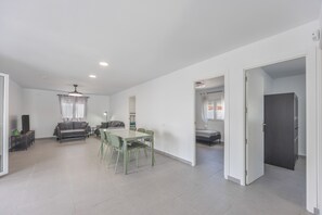 A spacious living area with a dining table, a sofa, and a TV.