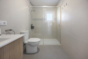 A modern bathroom with a shower, toilet, and sink.