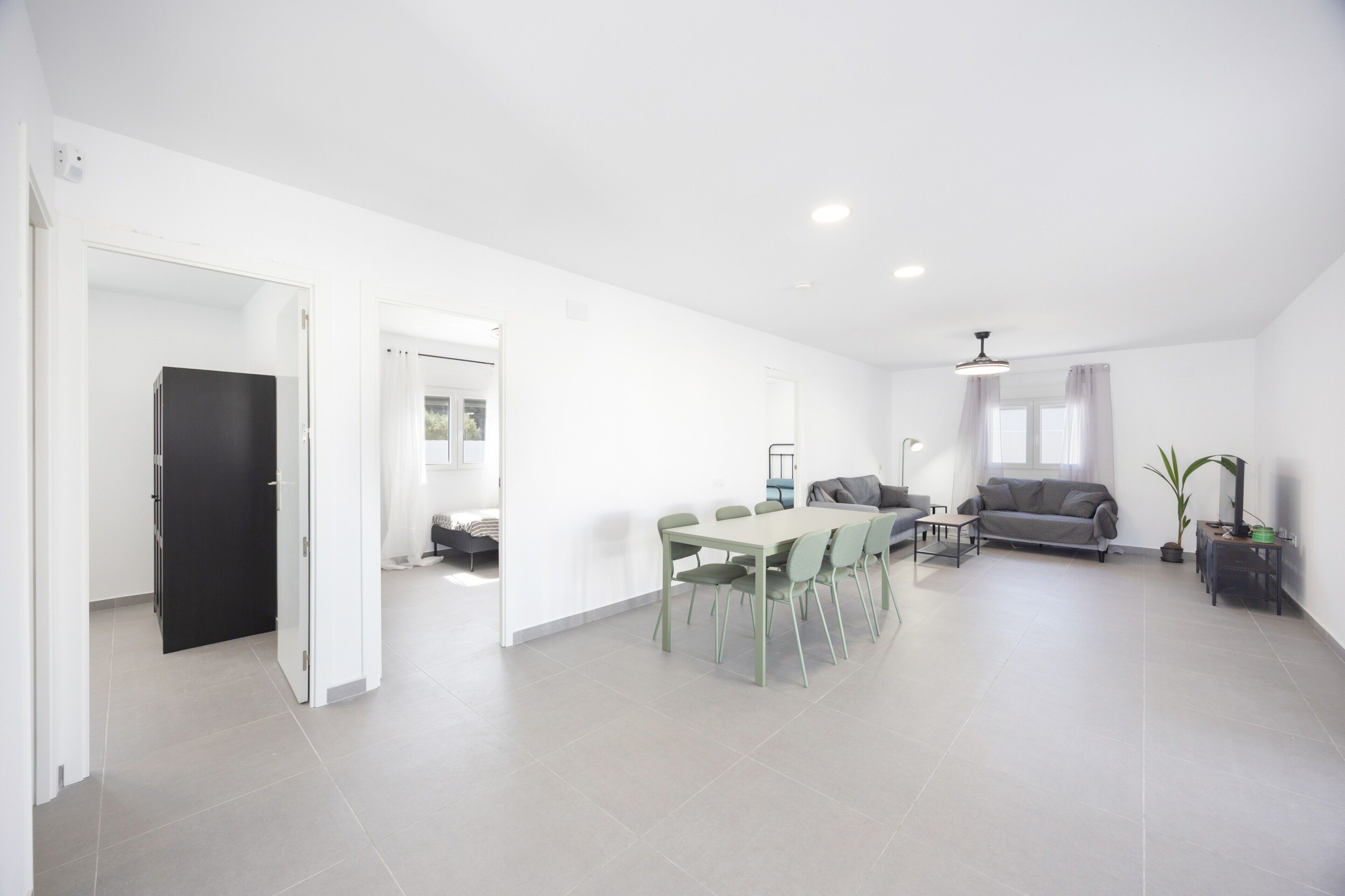 A spacious living area with a dining table, sofa, and a black door leading to another room.