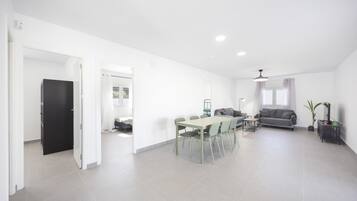 A spacious living area with a dining table, sofa, and a black door leading to another room.