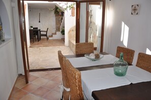 A dining area with a table set for four, a wicker chair, and a bottle on the table. - Rustic house, ideal for families, there are 4 golf courses in 15 qm. (Artà)