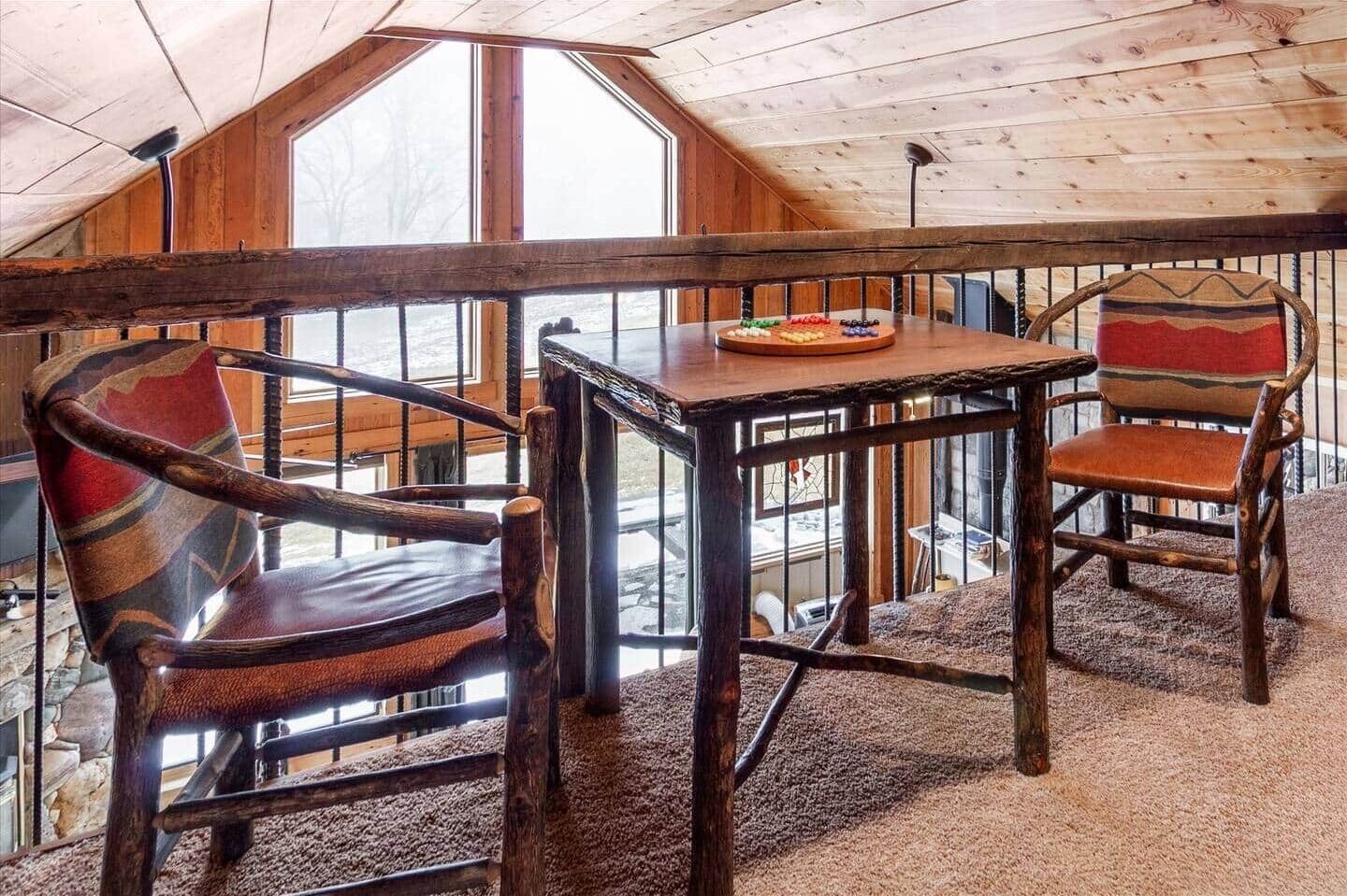 Un interno in legno con un balcone, un tavolo con un piatto e due sedie.