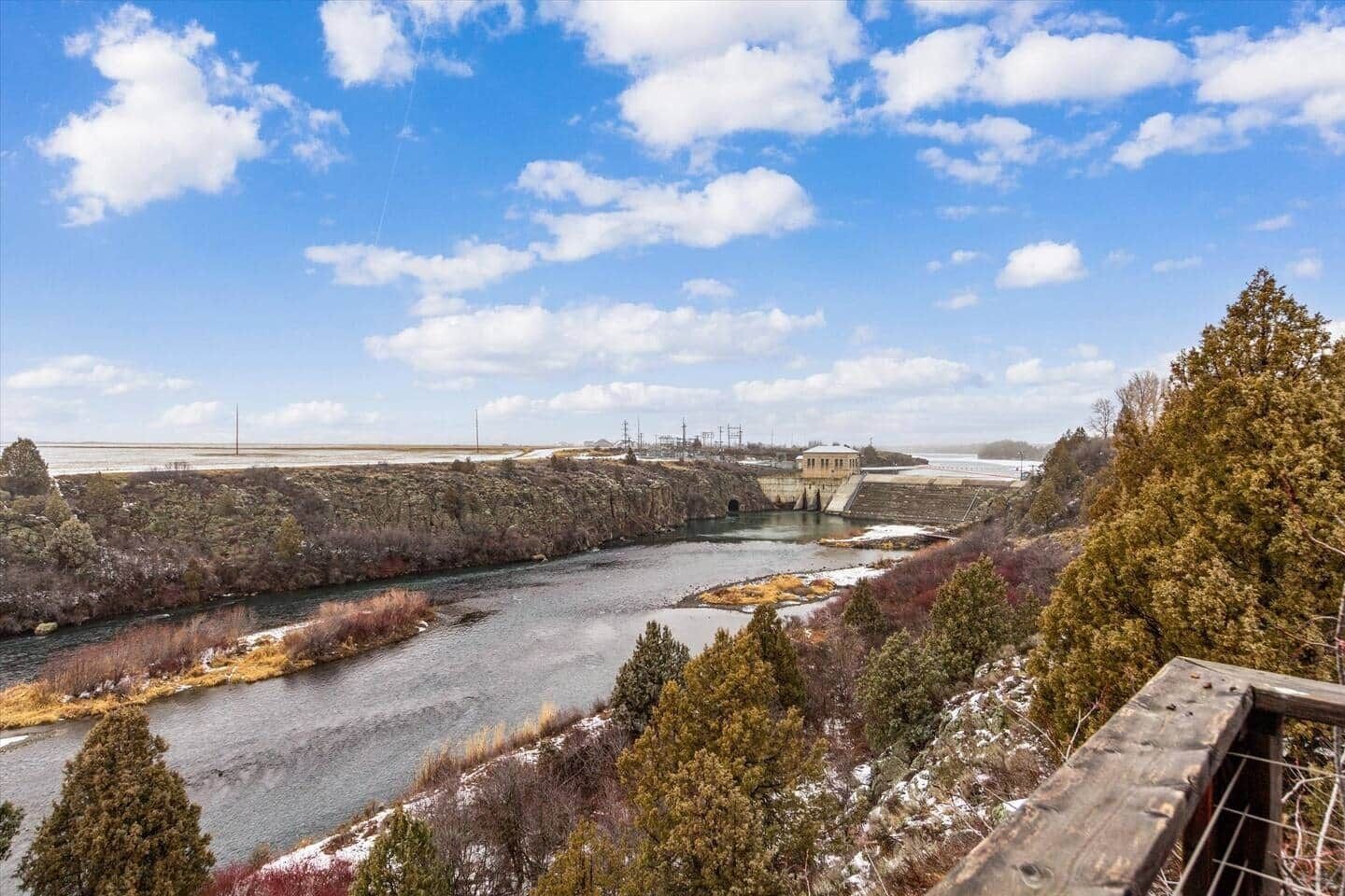 A river with a dam, trees, and a clear sky.