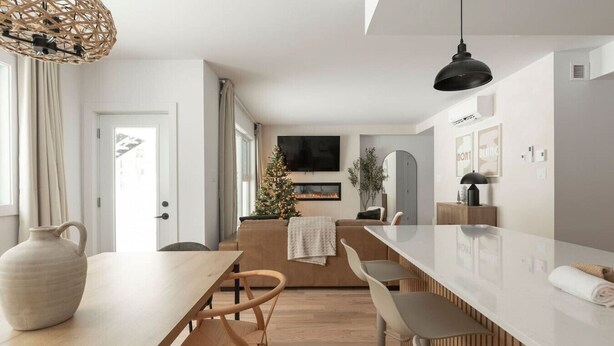 A modern kitchen with a long island, wooden chairs, a large vase, and a flat-screen TV. - Ski In/Out Mont-Blanc | Easy Après-Ski + Fire (Les Laurentides Regional County Municipality)