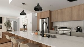 A modern kitchen with a large island, stainless steel appliances, and wooden cabinetry. - Ski In/Out Mont-Blanc | Easy Après-Ski + Fire (Les Laurentides Regional County Municipality)