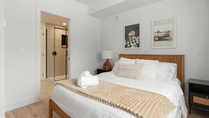 A bedroom with a bed, bedside tables, a lamp, and artwork on the wall. - Ski In/Out Mont-Blanc | Easy Après-Ski + Fire (Les Laurentides Regional County Municipality)