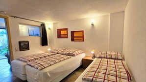 A compact hotel room with two beds, a small bedside table with a lamp, a window with curtains, and a wall-mounted picture. - Rollstuhlgerechte Ferienwohnung im Ferienpark (Dabel)
