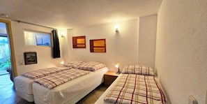 A compact hotel room with two beds, a small bedside table with a lamp, a window with curtains, and a wall-mounted picture. - Rollstuhlgerechte Ferienwohnung im Ferienpark (Dabel)