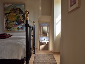 A bedroom with a bed, a painting, a mirror, and a view into the bathroom. - Alkis Farm AND Residence (Zakynthos)