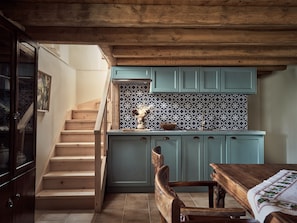 A kitchen with wooden cabinets, a tiled backsplash, and a wooden staircase. - Alkis Farm AND Residence (Zakynthos)
