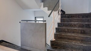 A staircase with a handrail and a fire extinguisher on the wall. - Deluxe With Twin Bed Balewadi High (Pune)