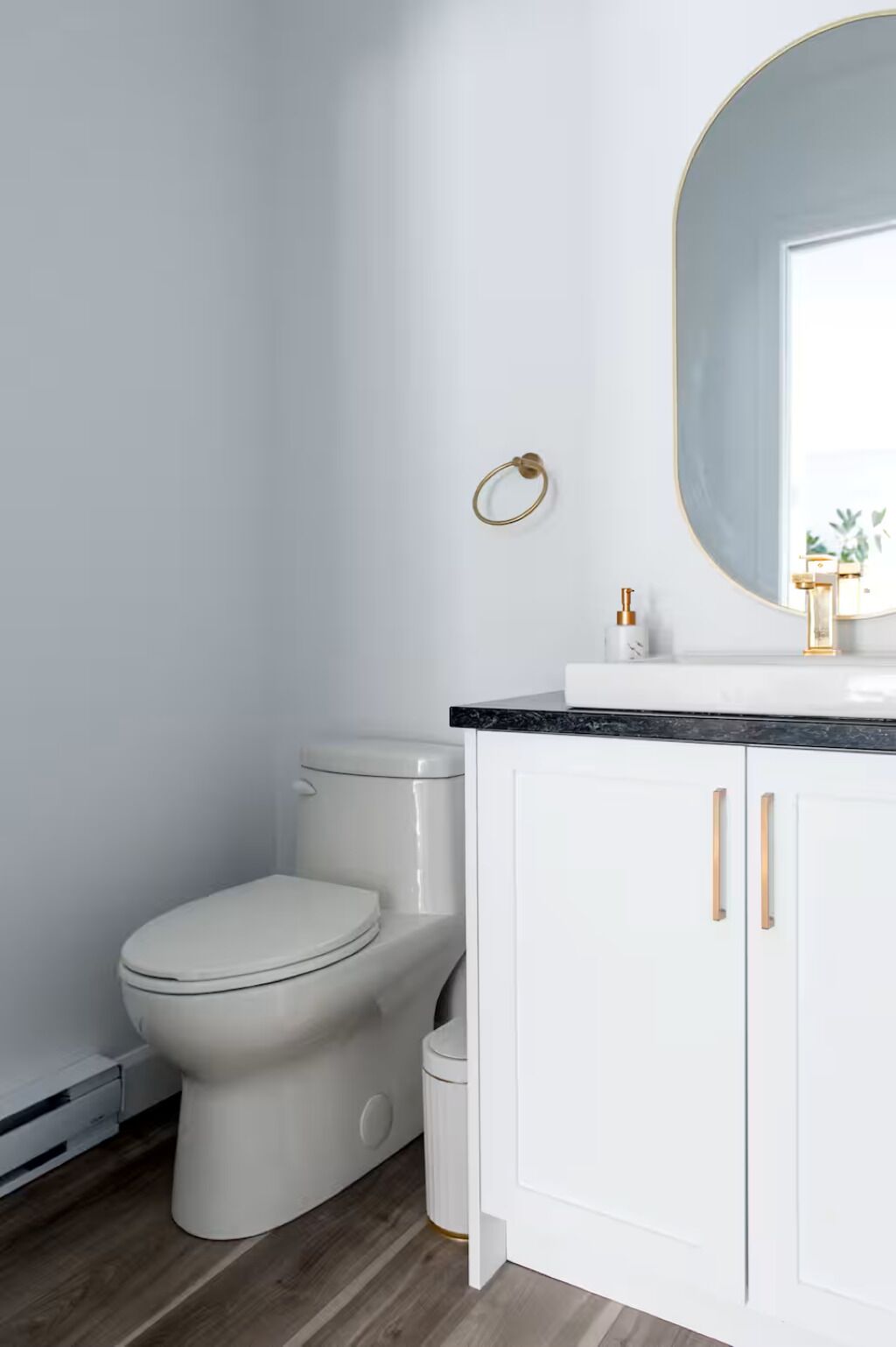 A bathroom with a toilet, a sink with a mirror, and a cabinet.