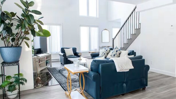 Un salon moderne avec un canapé bleu, une table basse et un escalier.