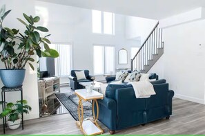 Uma sala de estar moderna com um sofá azul, uma mesa de centro e uma escada.