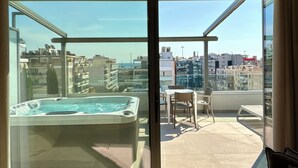 Ein Balkon mit Whirlpool, Tisch und Stühlen mit Blick auf die Stadtlandschaft.